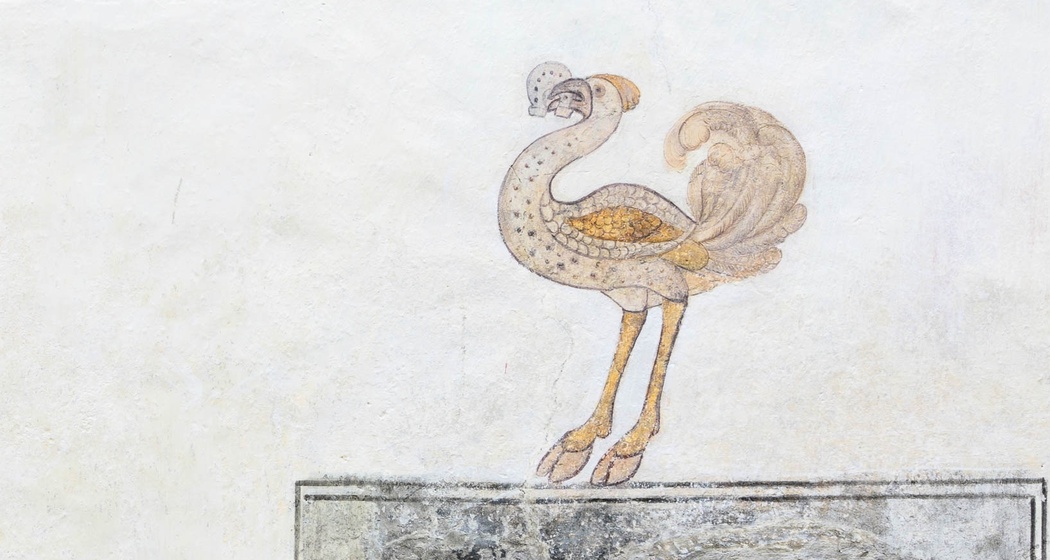 Fassadendetail: Strauss mit Hufeisen im Schnabel.