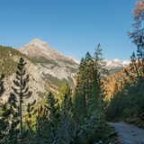 Le chemin serpente depuis La Drossa le long de la pente en direction de l'Alp la Schera. En arrière-plan, le Piz dal Fuorn.