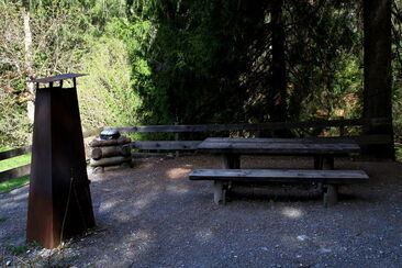 Grillplatz mit Steinbänkli rundherum auf einem Kiesplatz.