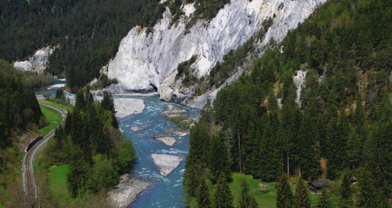 Der Rhein schlängelt sich durch die Rheinschlucht. Rundherum Felswände und Wald.