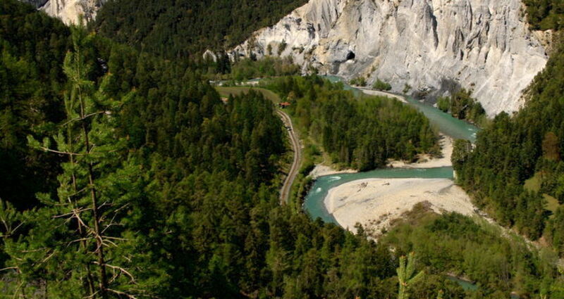 Der Rhein schlängelt sich durch die Rheinschlucht. Steile Felswände und Wald rundherum.