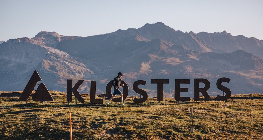 Ein Trailrunner läuft vor dem Klosters-Logo auf dem Gotschna