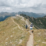 deux coureurs de trail courent le long de la crête. En arrière-plan : le Jakobshorn
