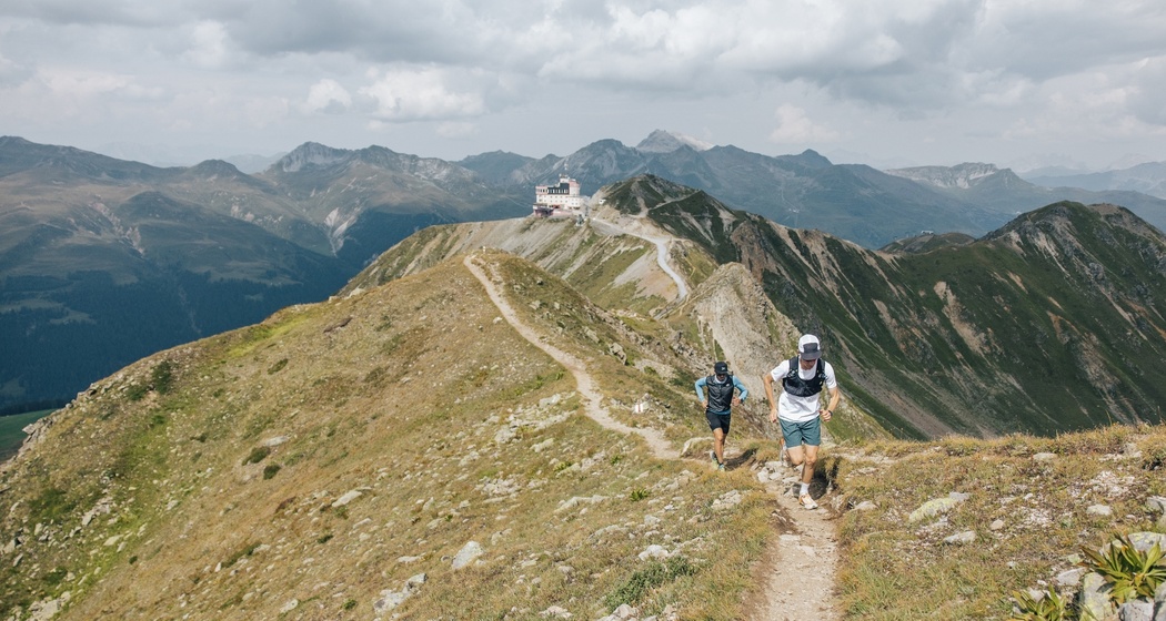 zwei Trailrunners laufen den Grat entlang. Im Hintergrund: das Jakobshorn