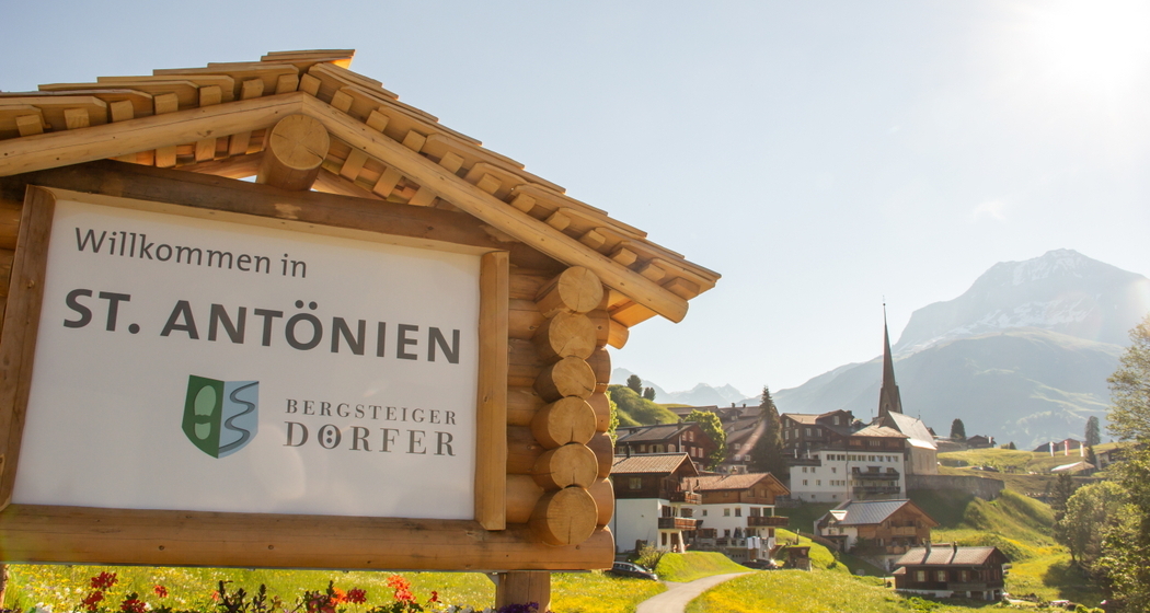 Ortstafel des Bergsteigerdorfes St. Antönien, im Hintergrund das Dorf