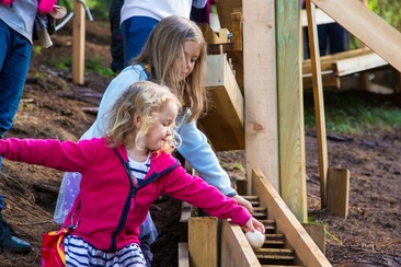 Das Foto zeigt zwei Mädchen die eine Kugel der Bahn runterlaufen lassen