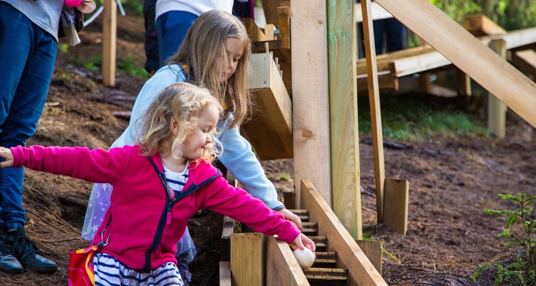 Das Foto zeigt zwei Mädchen die eine Kugel der Bahn runterlaufen lassen
