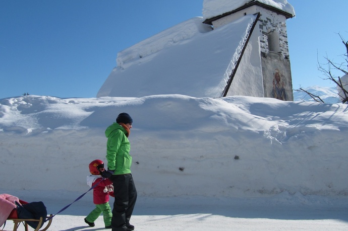 Das Foto zeigt die Kapelle St. Martin im Winter und ein Vater läuft mit ihrer Tochter vor der Kapelle her