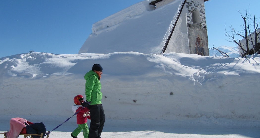 Das Foto zeigt die Kapelle St. Martin im Winter und ein Vater läuft mit ihrer Tochter vor der Kapelle her