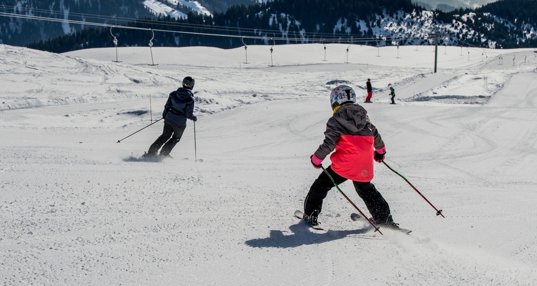 Das Foto zeigt ein Mann und ein junges Mädchen, welches die Piste neben dem Skilift Miret abfahren