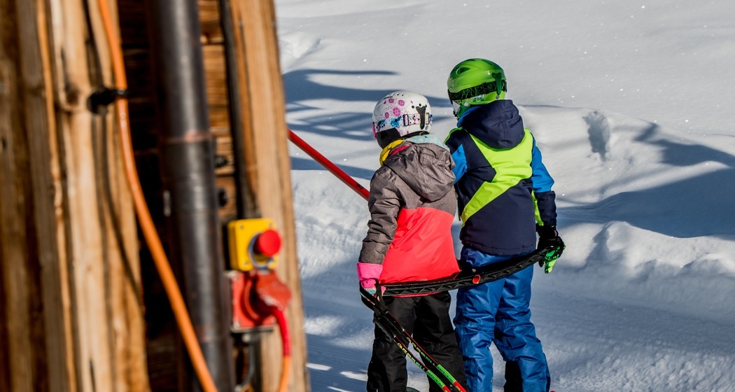 Das Foto zeigt zwei junge Kinder die auf dem Skilift Parli eingestiegen sind