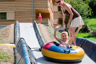 Das Foto zeigt eine Mutter die ihr Kind der Tubingbahn runter schiebt
