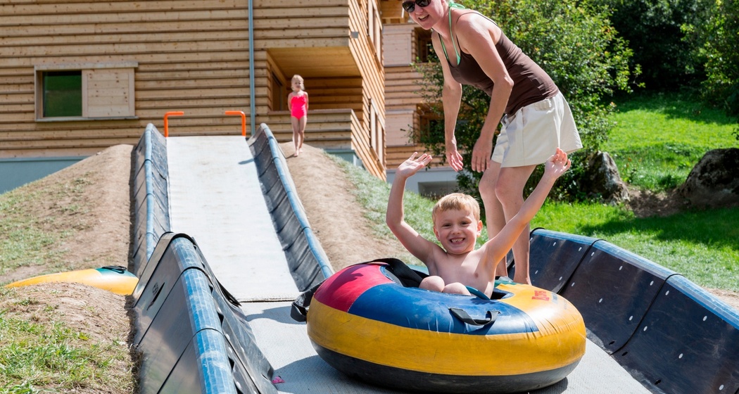 Das Foto zeigt eine Mutter die ihr Kind der Tubingbahn runter schiebt