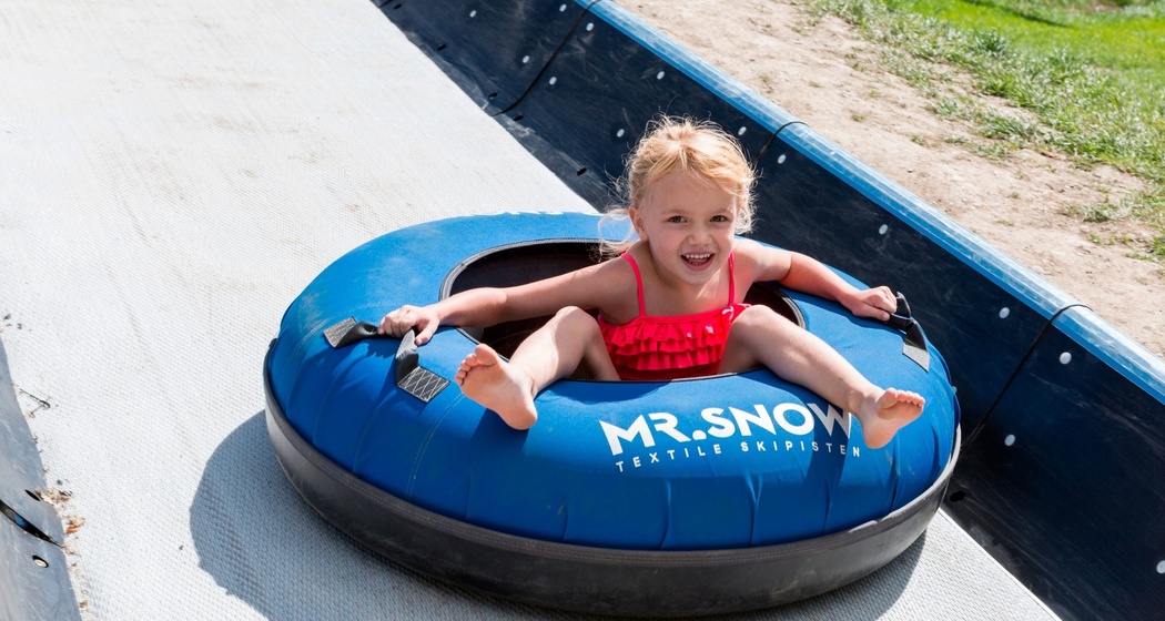 Das Foto zeigt ein junges Mädchen, welches die Tubingbahn runter fährt