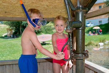 Das Foto zeigt zwei Kinder die mit einer Wasserpumpe spielen