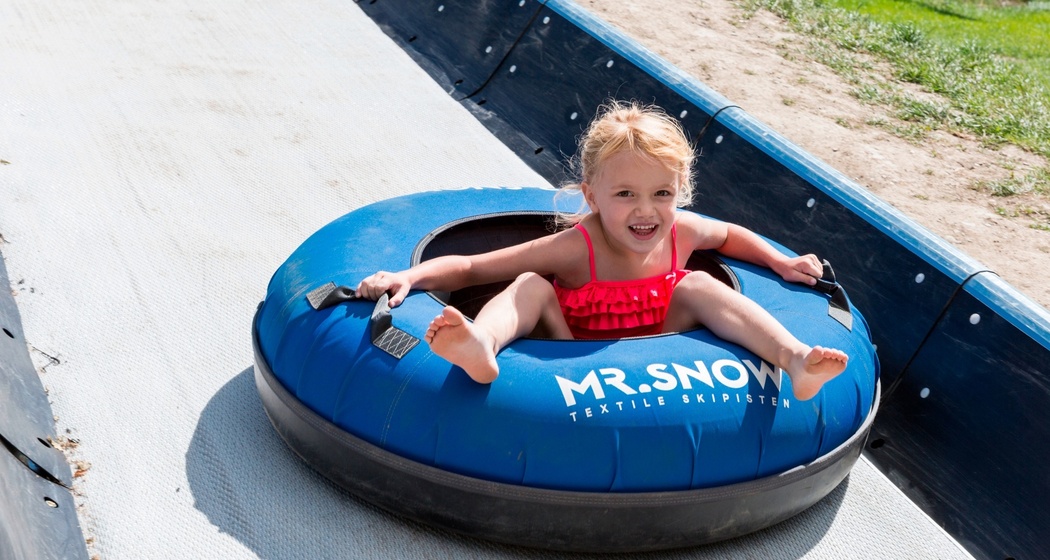 Das Foto zeigt ein junges Mädchen, welches die Tubingbahn runter fährt