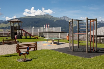 Das Foto zeigt den Spielplatz beim Schulhaus in Brigels mit einer Rutsche und Klettermöglichkeit