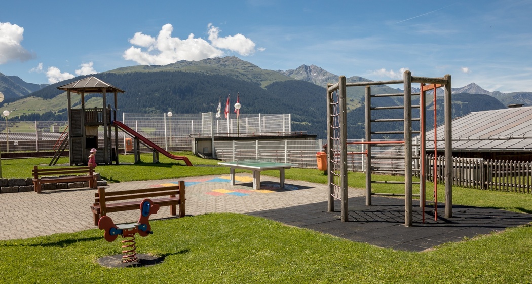 Das Foto zeigt den Spielplatz beim Schulhaus in Brigels mit einer Rutsche und Klettermöglichkeit