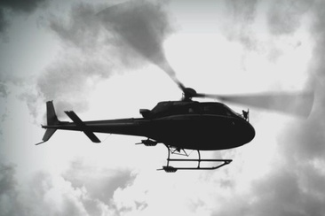 Das Foto zeigt ein Helikopter von unten der nah am Boden vorbeifliegt