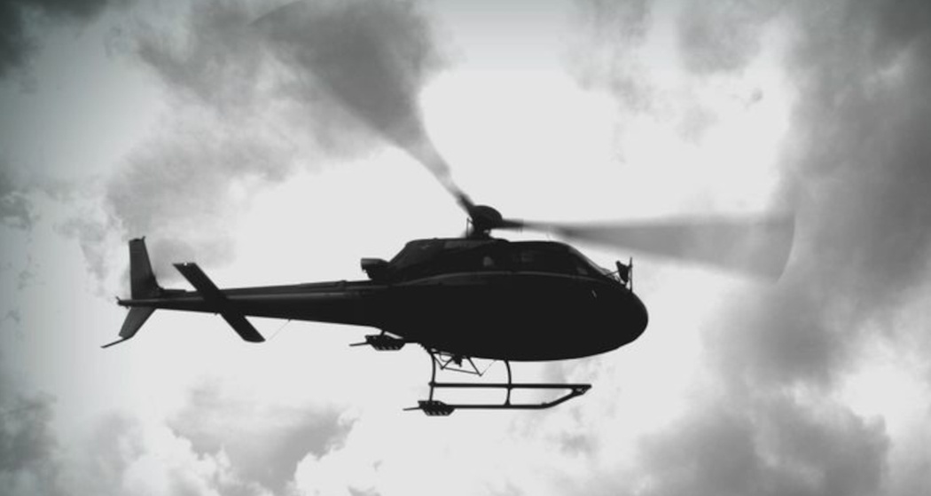 Das Foto zeigt ein Helikopter von unten der nah am Boden vorbeifliegt