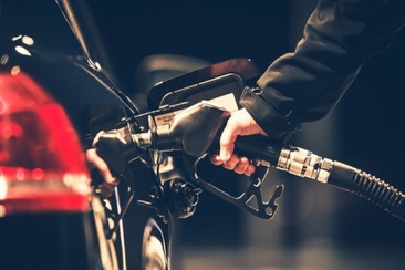 Das Foto zeigt eine person die ihr Auto mit Benzin tankt