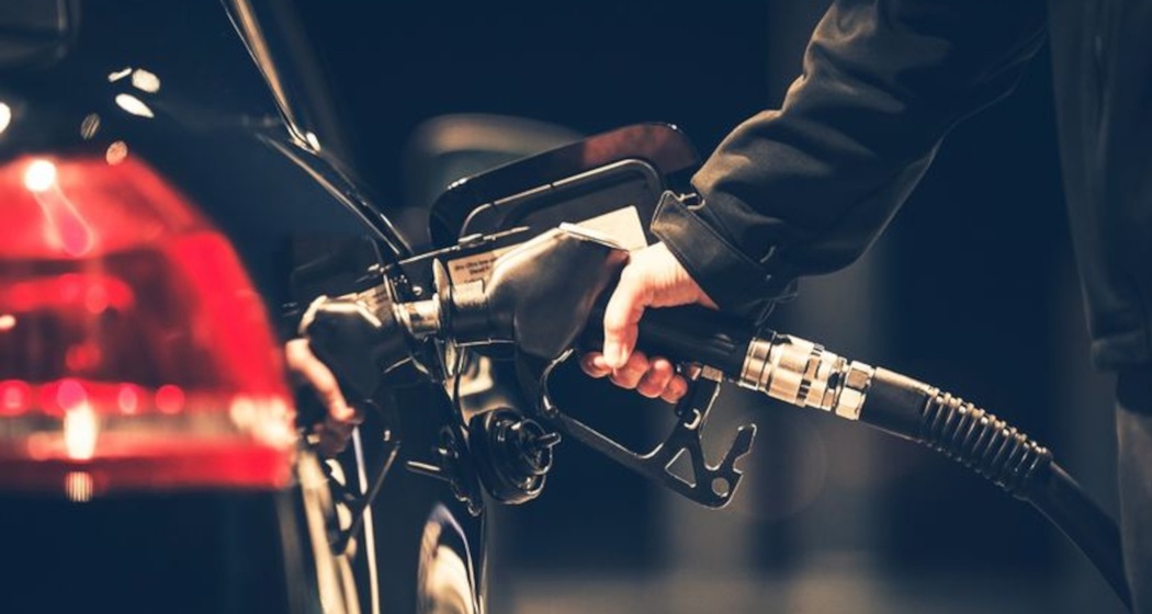 Das Foto zeigt eine person die ihr Auto mit Benzin tankt