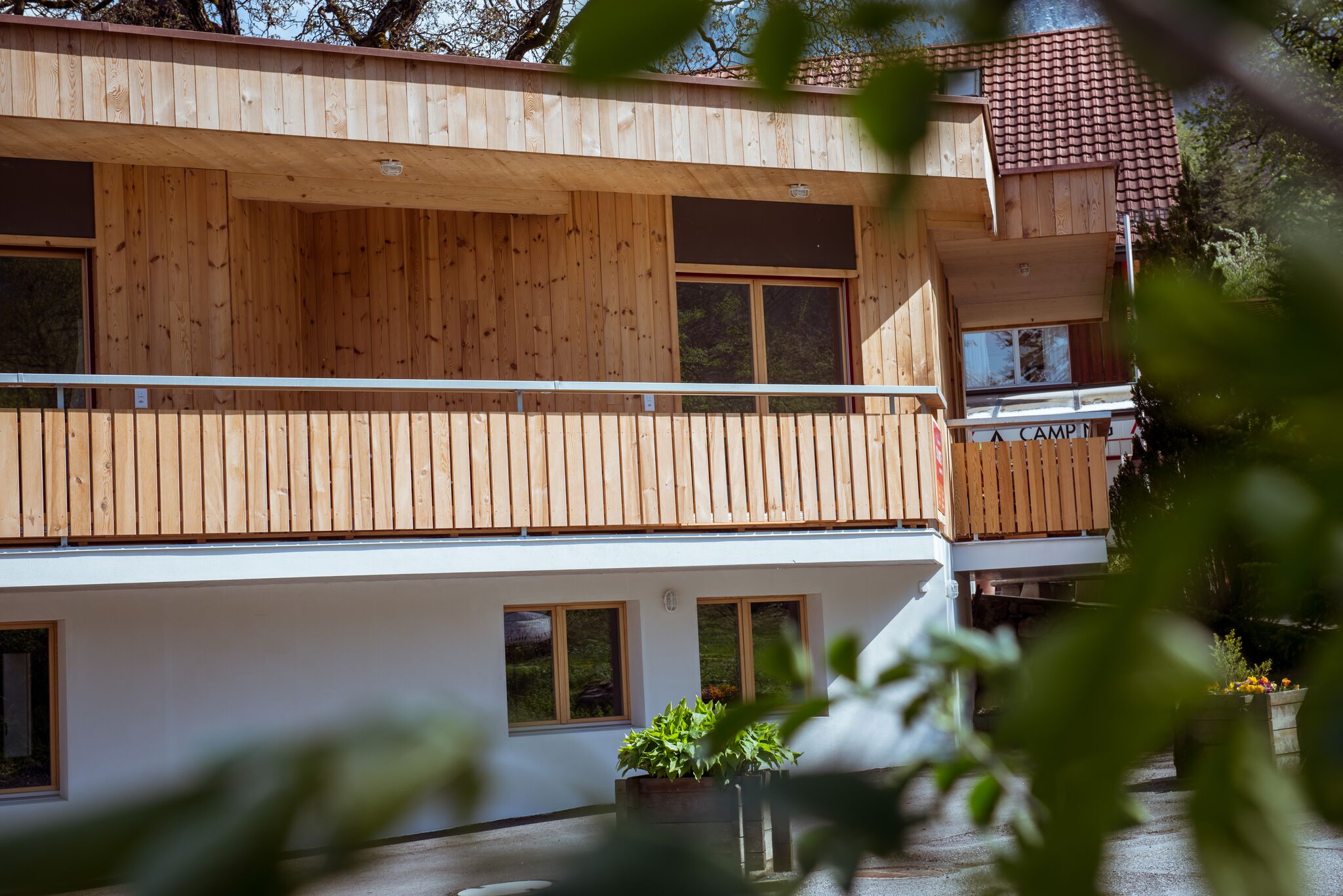 Außenansicht des Gästehauses beim Camping Mittagsspitze mit Holzfassade und Balkon in naturnaher Umgebung